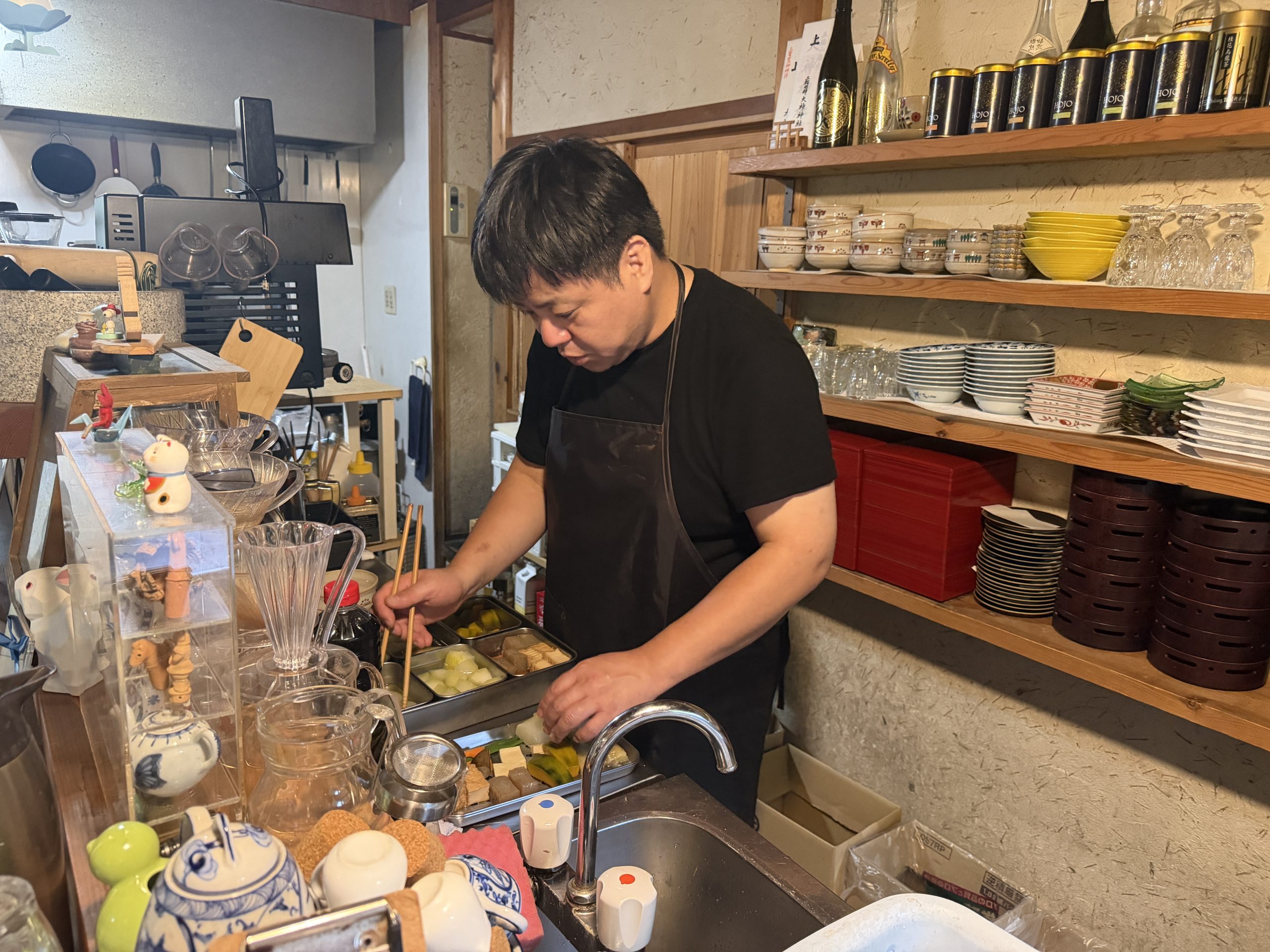 厨房で男性が煮物や料理の仕込みをしている様子。