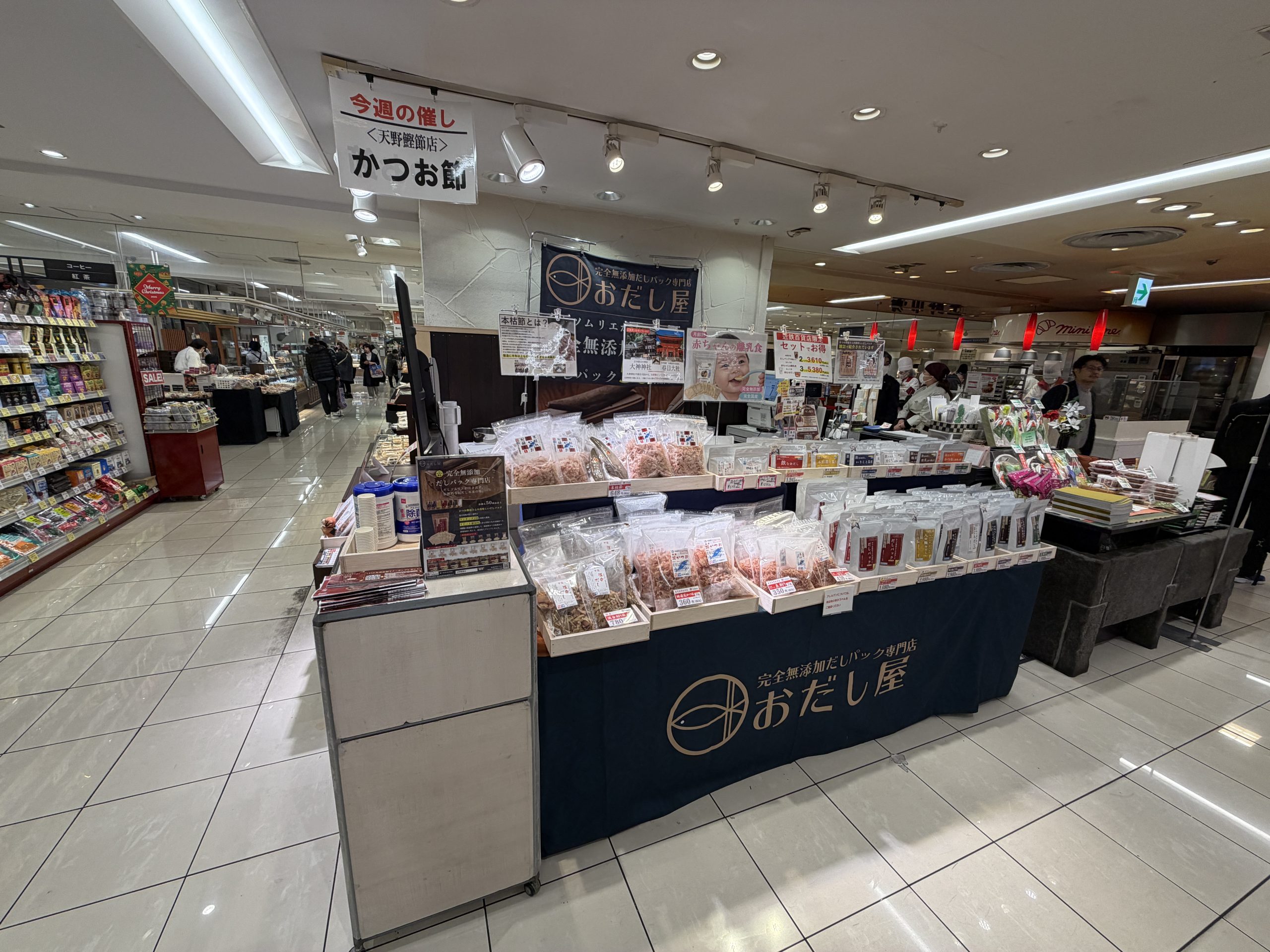 百貨店の催事場に出店した「おだし屋」の売り場。かつお節やだしパックが並び、今週の催しとしてかつお節が紹介されています。
