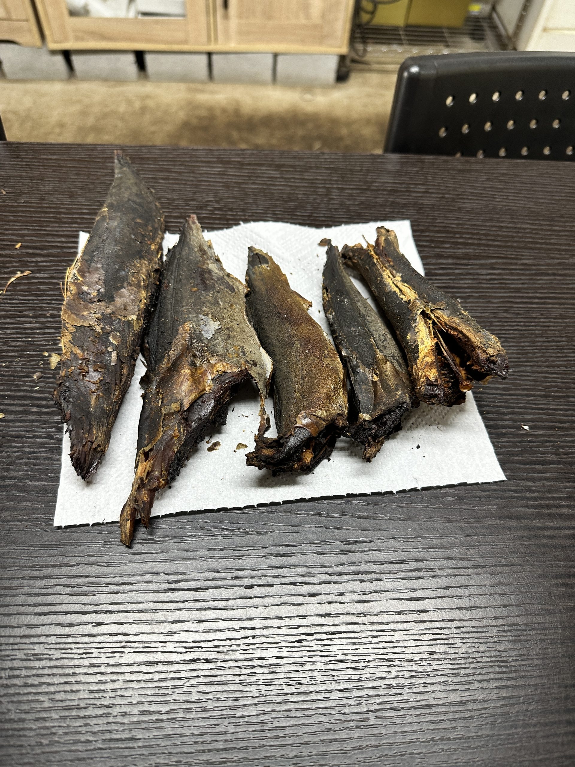 紙の上に並べた鰹節の試作品のようなもの。表面の色や乾き具合を確認している様子です。